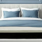 Modern bedroom with blue walls, white bed, and wooden furniture. Pressure's Off mattress for pain relief is featured.